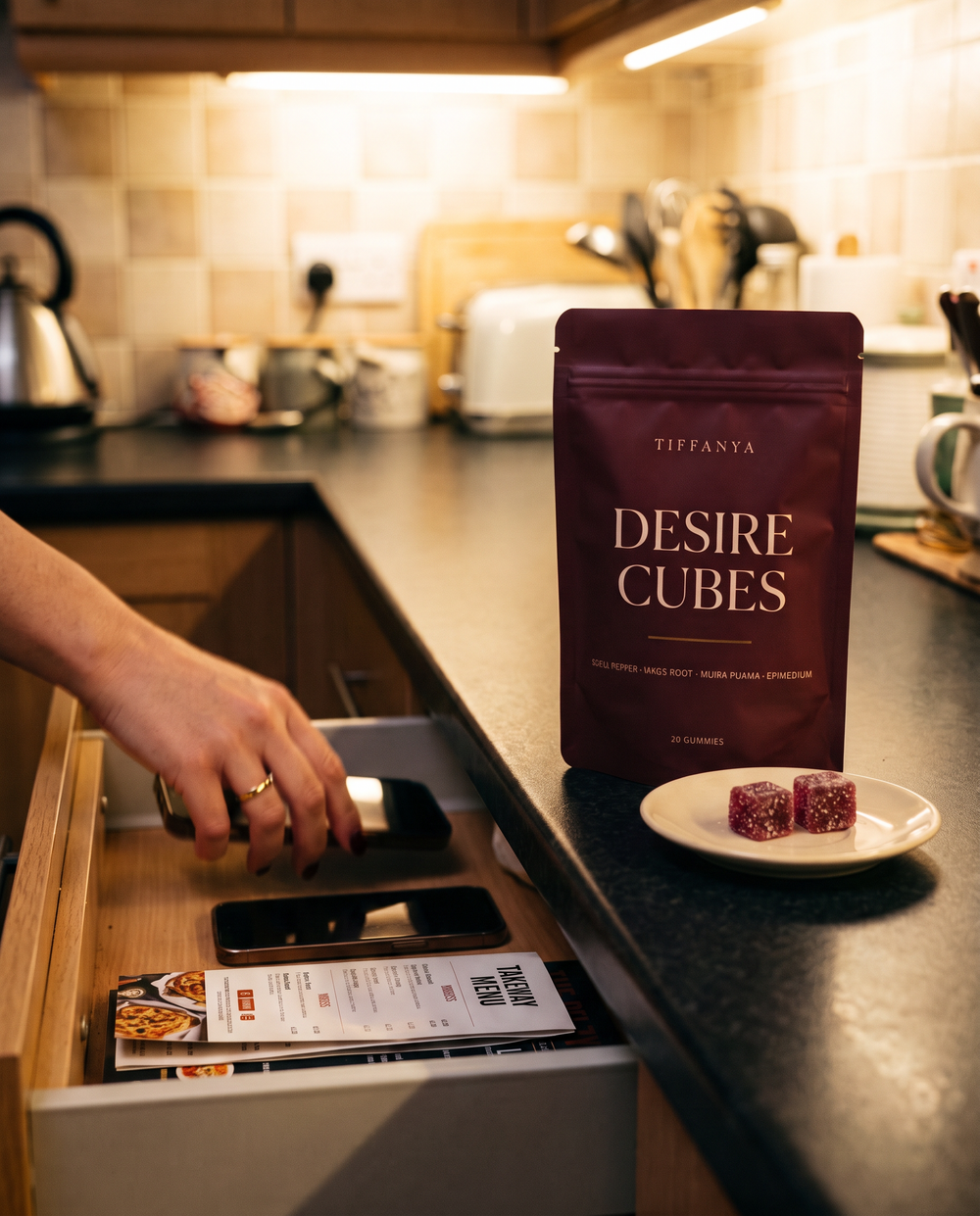 Two phones put away in a kitchen drawer next to a pouch of Desire Cubes